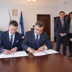 Zbigniew Jagiełło - prezes zarządu PKO Banku Polskiego oraz Radosław Stępień wiceprezes Zakładu Ubezpieczeń Społecznych siedzą przy stole i podpisują porozumienie.